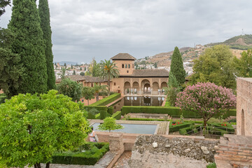 Fototapeta na wymiar View at the Partal Palace or Palacio del Partal , a palatial structure around gardens and water lake inside the Alhambra fortress complex located in Granada, Spain