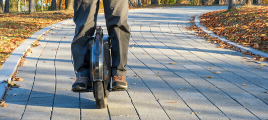 A man rides electric unicycle in city park. © TATIANA KIM