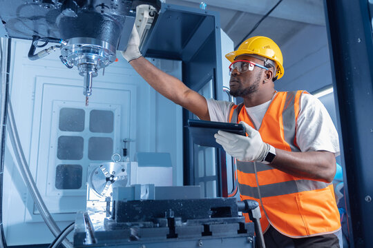 Control and Setting of CNC equipment, Engineer african Industry work with tablet computer on modern automatic machine