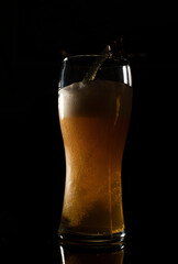 main tenant un verre de bière sur un fond noir