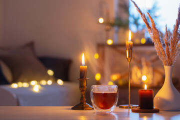 hot tea in thermo glass with christmas decor and burning candles at home