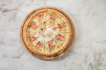 Obraz na płótnie Canvas Fresh pizza carbonara with ham and scrambled egg on the concrete background