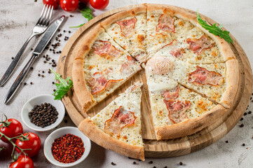 Fresh pizza carbonara with ham and scrambled egg on the concrete background