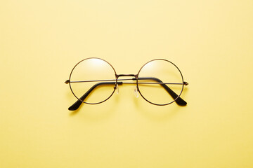 Glasses in round thin metal frame isolated on yellow surface.