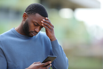 Concerned black man reading bad news on phone