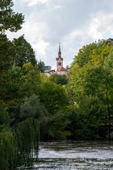 Fototapeta na wymiar La rivière Pivka et le clocher de l'église Sainte Catherine autour des grottes de Postojna en Slovénie à l'automne