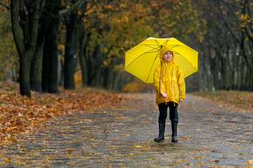 Full-length of child in the rain on autumn park background.