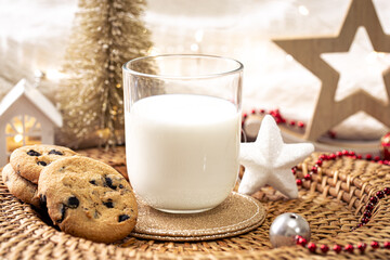 Christmas cookies and glass of milk for Santa on holiday blurred background.