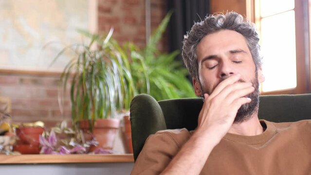 Close-up of a tired handsome man falling asleep having a nap on a chair at home