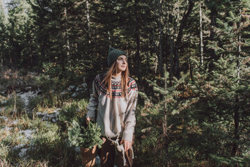 Contemplative woman with basket of spruce twigs in forest