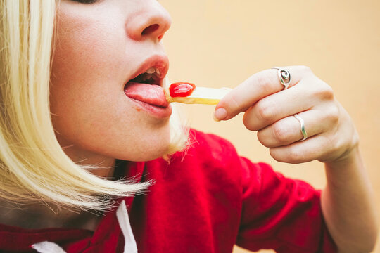 Woman eating French fries with ketchup