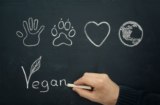 Man drawing vegan concept on blackboard, close-up