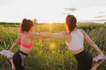 Woman with instructor doing stretching exercise on sunny day