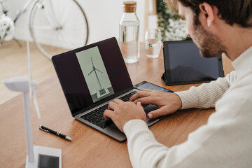 Businessman working on wind turbine model over laptop in office