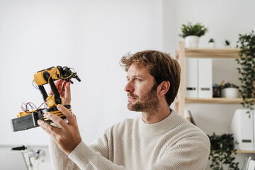 Engineer analyzing robotic arm in office