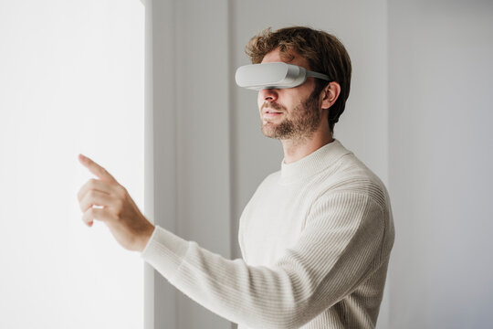 Businessman with VR goggles touching interactive screen in office