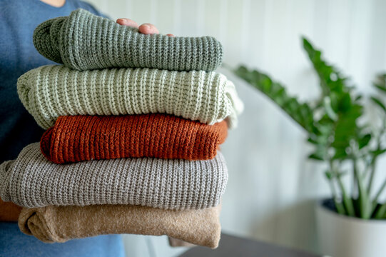 Man holding woolen sweaters at home