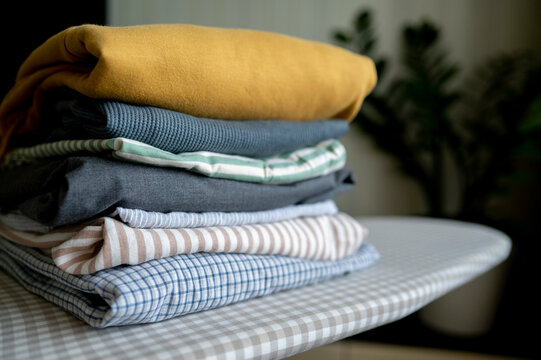 Stack of folded clothes on ironing board at home