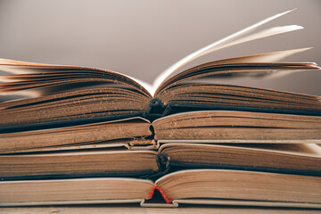 Open old books stacked, close-up on blurred background.