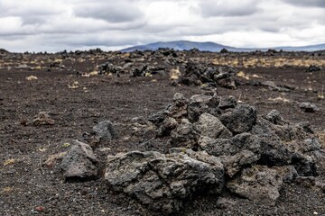Rocky wasteland in Iceland with silhouettes of distant hills in the background under a cloudy sky