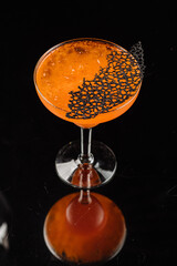 Cool orange cocktail in glass on the black background