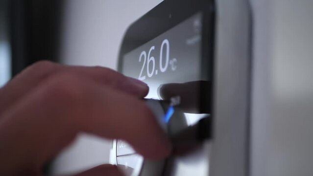 A woman adjusts smart thermostat gadget at home