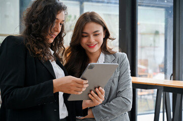 Caucasian businesswoman looking at tablet screen, sharing ideas with her colleague.