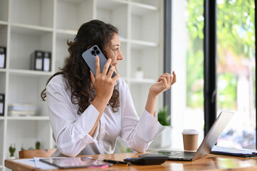 Professional caucasian businesswoman is in the office having a phone call with her client.