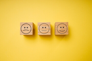 Smile and sad faces on wooden block cubesisolated on yellow background
