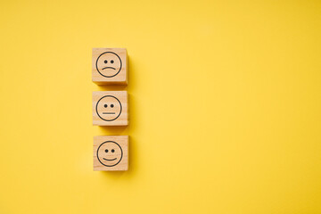 Wooden blocks with face symbols on yellow background, evaluation, increase rating