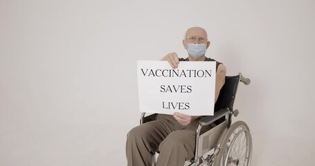 Old man sitting in a wheelchait on beige background