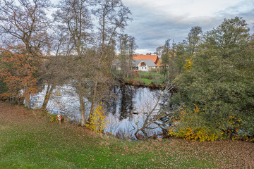 Aerial view on a little village in Europe, private houses. Multicolored trees in autumn, and green grass, forest, wild nature, river, contrasts. Cozy atmosphere. 