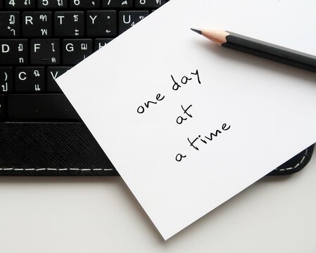 Pen on keyboard with handwritten text ONE DAY AT A TIME, concept of dealing with each day problems as they come, less worry about future or expect things to change overnight