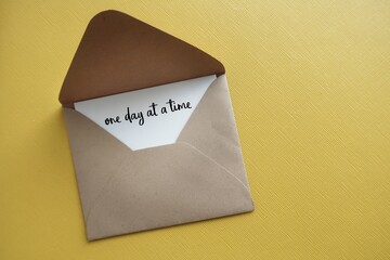 Craft envelope with handwritten text card ONE DAY A TIME, concept of dealing with each day problems...