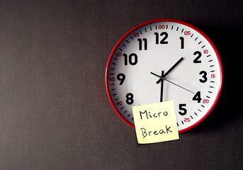 On copy space gray wallpaper, clock with stick note written MICRO BREAK, to break up from tasks or...