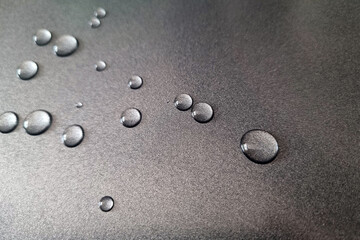 Fototapeta na wymiar Water droplets on a gray metal surface.