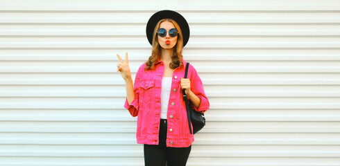 Portrait of stylish young woman model blowing her lips sending sweet air kiss wearing pink jacket,...