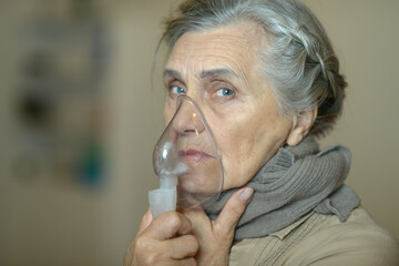 Senior woman using a nebulizer makes inhalation 