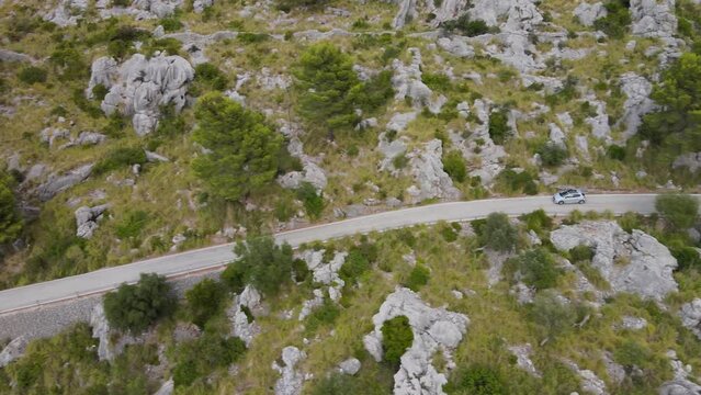 Long sideways panning shot following car peugeot 208 down winding road at Sa Calobra, Mallorca, Spain