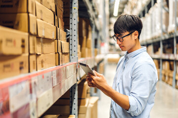 Portrait asian engineer man shipping order detail on tablet check goods and supplies on shelves...