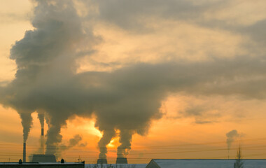 Industrial landscape in Russia. Smoke from Cogeneration rises very high against an orange evening sky at sunset