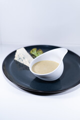 blue cheese broccoli soup white bowl elegant black plate portion