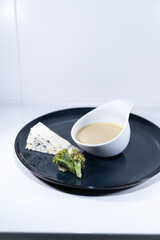 blue cheese broccoli soup white bowl elegant black plate portion
