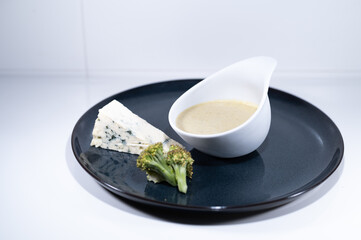 blue cheese broccoli soup white bowl elegant black plate portion
