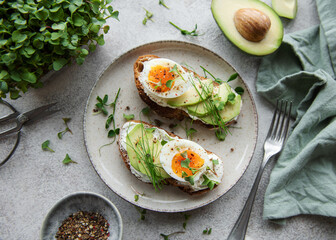 Bread toast, boiled eggs, avocado slice, microgreens on a plate