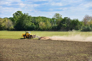 Yellow tractor preparing land for sowing.