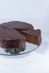 sacher torte chocolate Viena brown portion slice white background, cristal plate