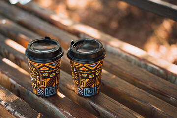 Background two glasses of takeaway coffee on wooden bench.