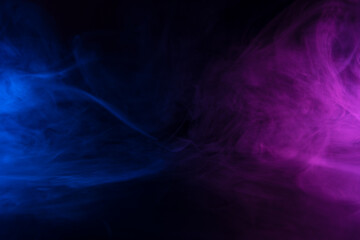 Clouds of blue and purple colored smoke swirling on black table background with reflection
