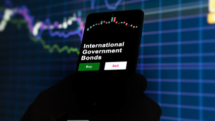 An investor's analyzing the international government bonds etf fund on screen. A phone shows the ETF's prices international government bonds to invest